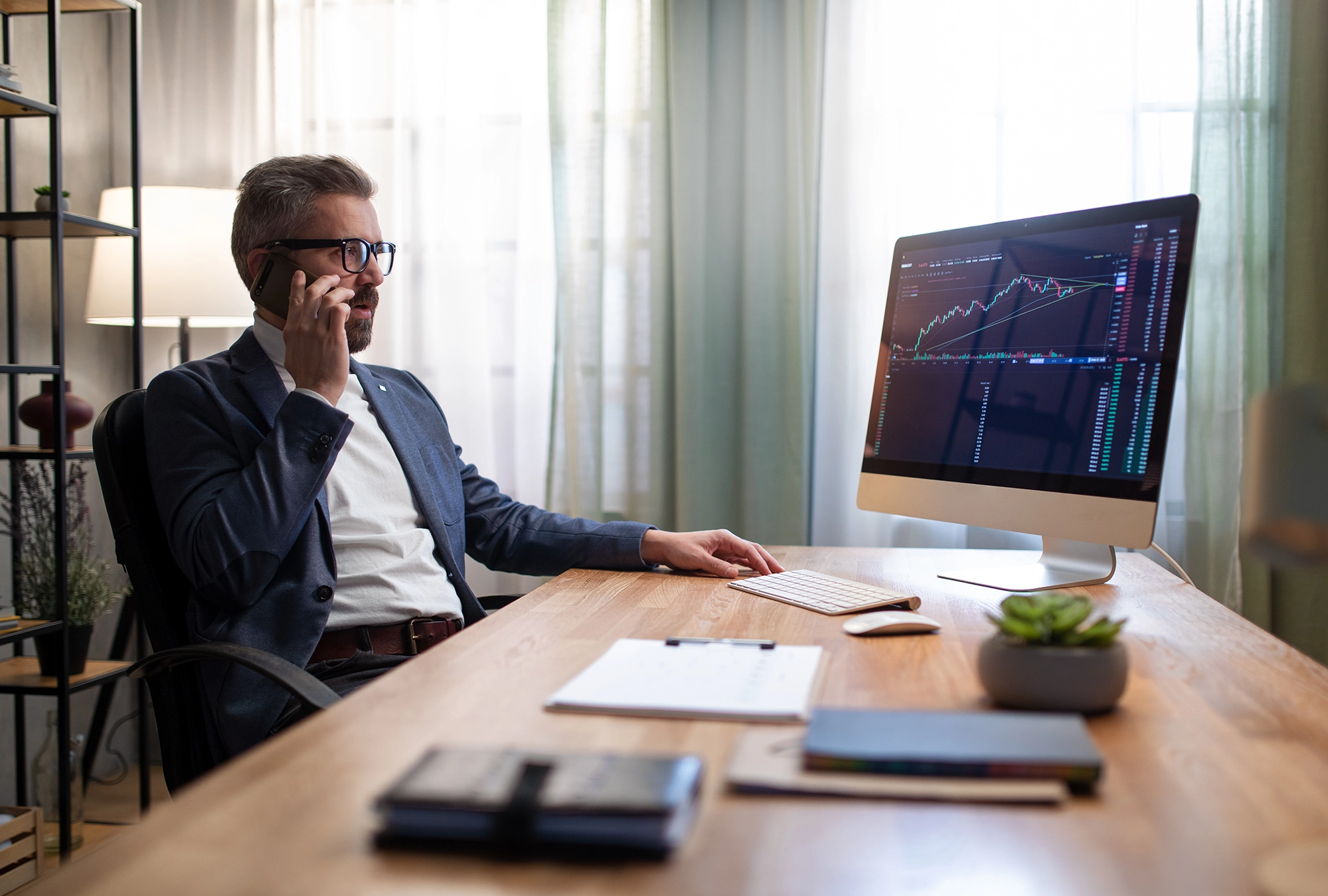 guy on the phone and looking at computer with investment programs