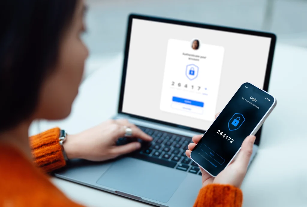 image of woman with laptop and holding phone performing 2-factor authentication login