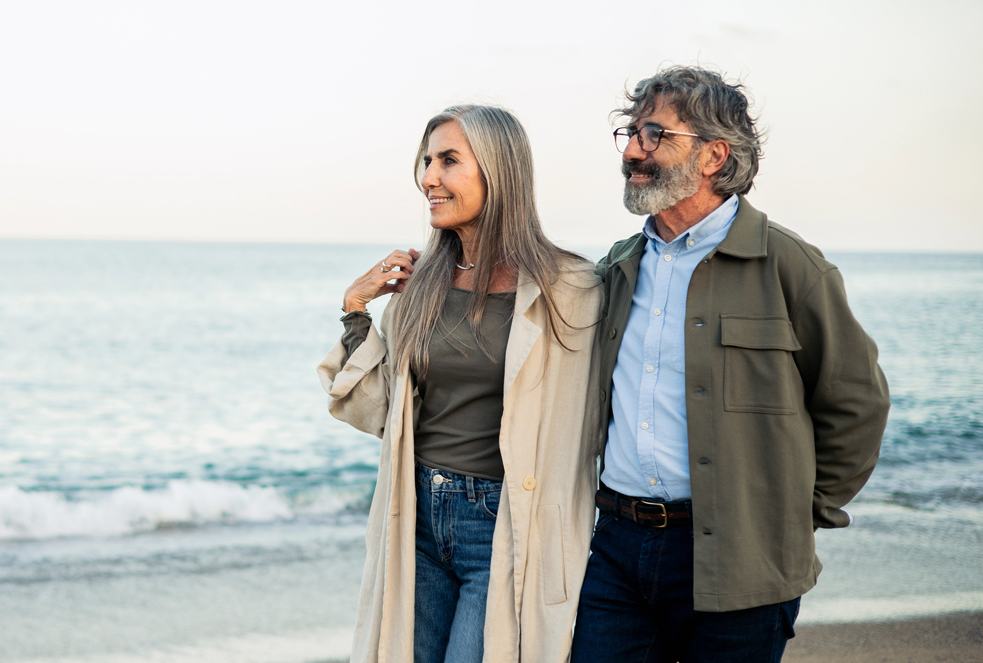 husband and wife enjoying retirement, walking on the beach