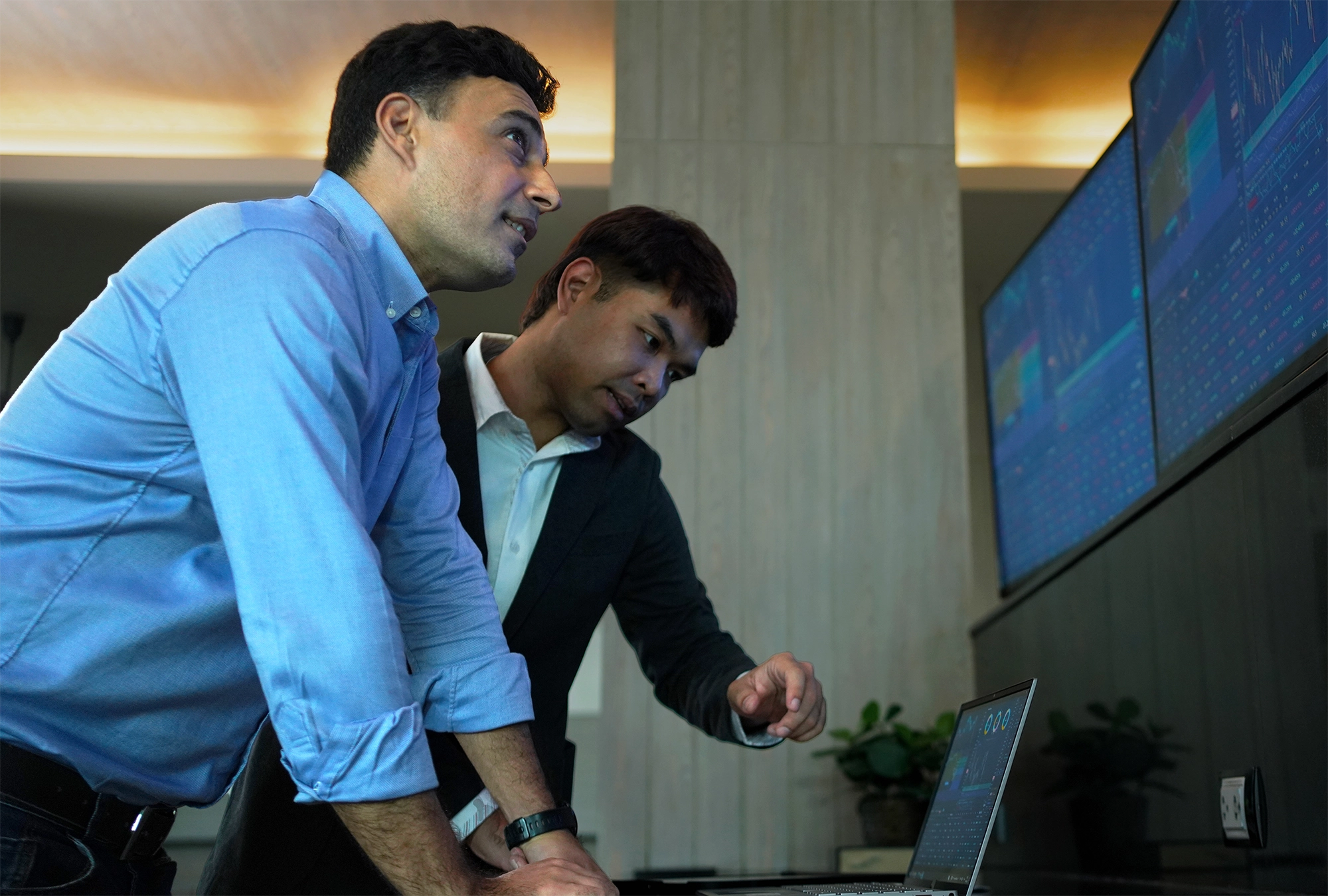 two financial advisors looking at stocks on monitors