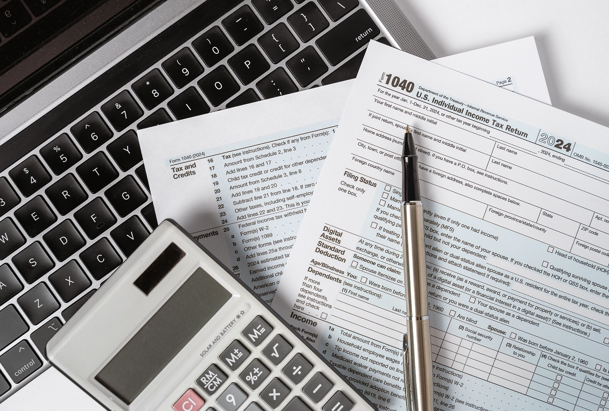 tax documents, pen and calculator on table with laptop