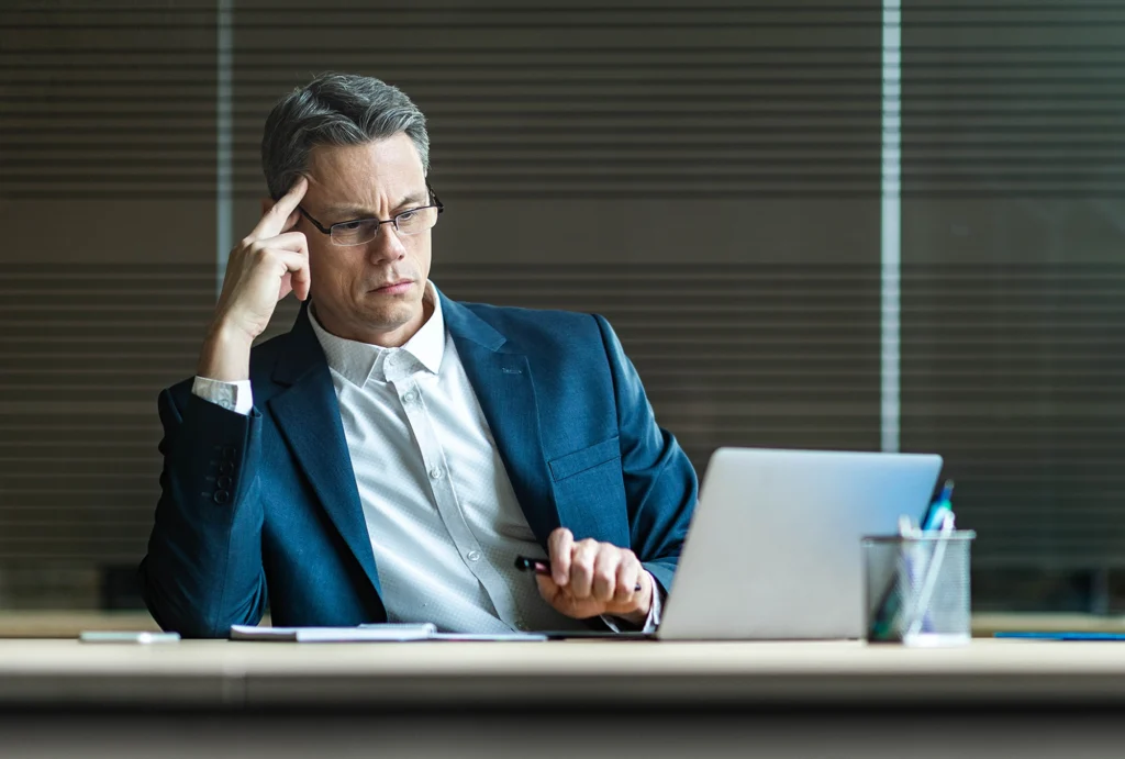 man sitting at desk thinking hard about something