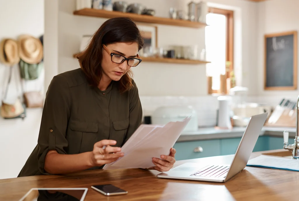 Woman sitting at kitchen table looking at financial papers