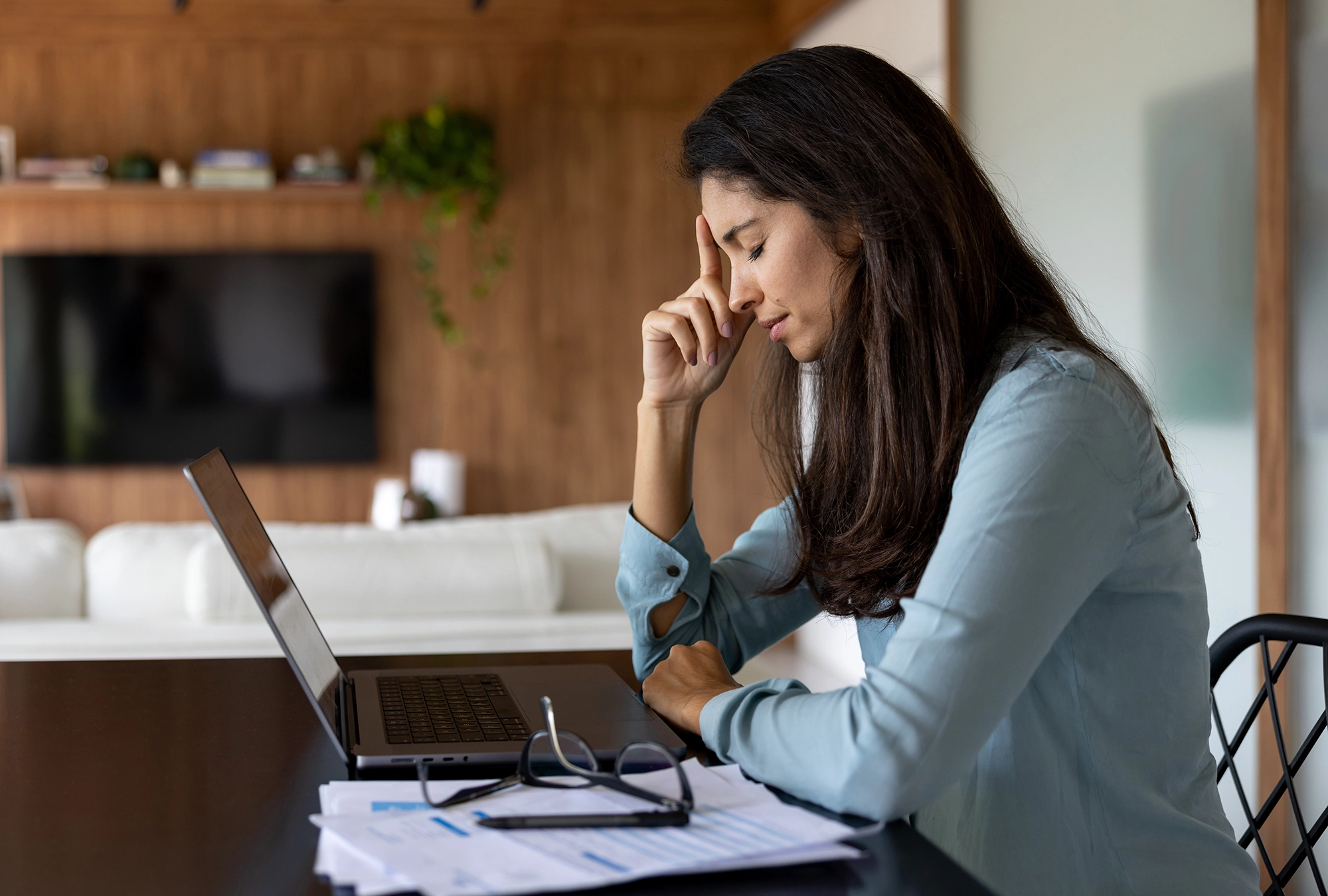 worried woman sitting at a table looking at her finances